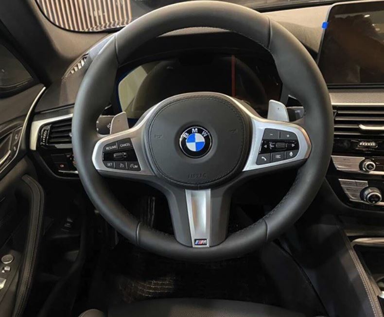 Vô-lăng của ô tô BMW 530i M Sport 2023 là loại 3 chấu thể thao M bọc da kết hợp với 2 lẫy chuyển số, tích hợp cùng các phím bấm vật lý